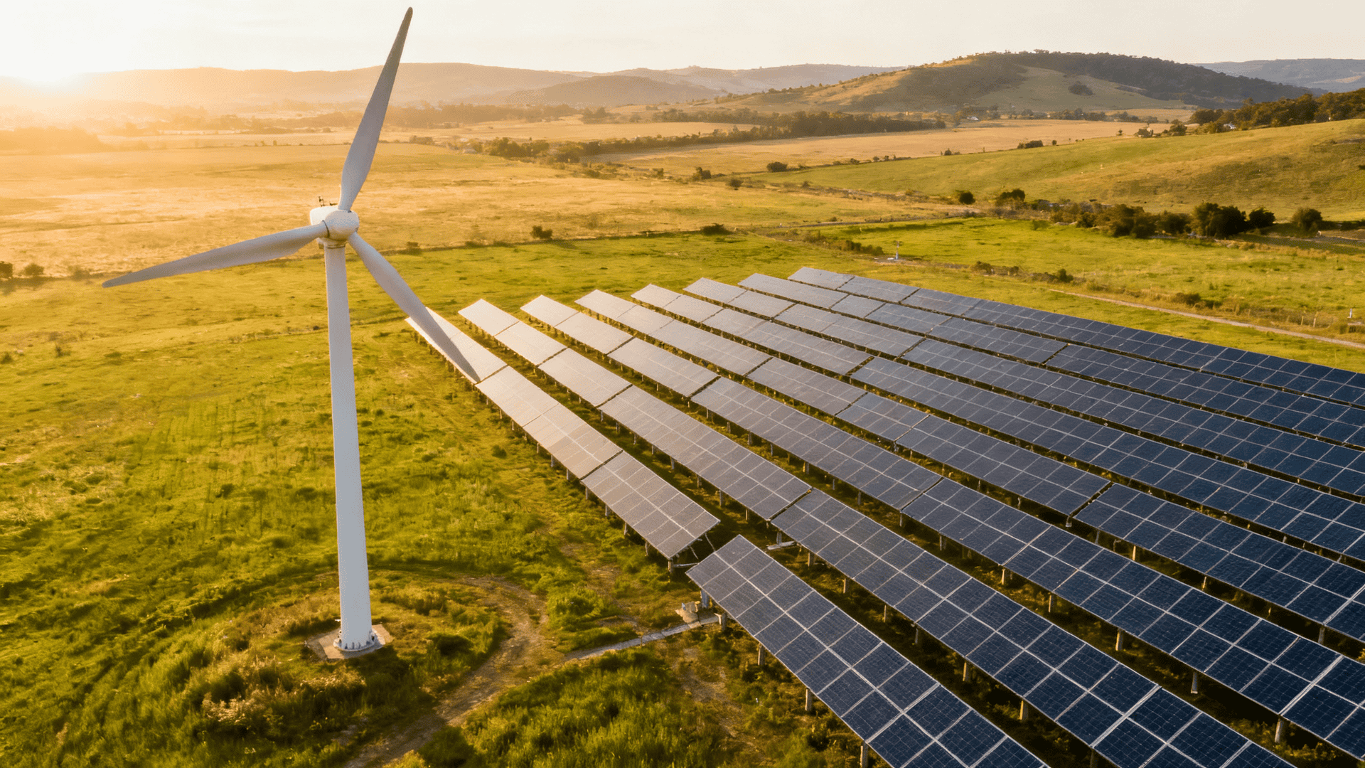 Wind turbine and solar panel array side by side in a rural landscape